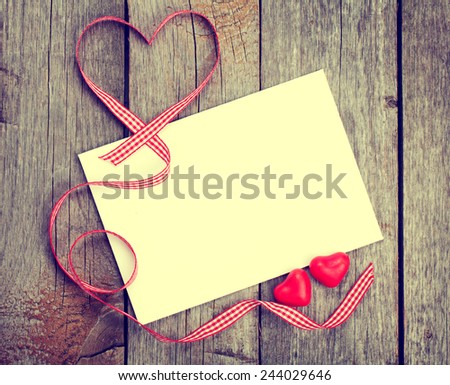 Valentine\'s day blank gift card and red candy hearts on wooden background. Toned