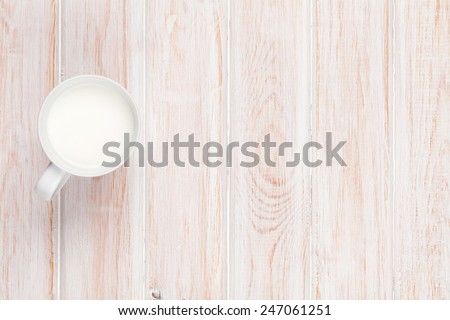 Cup of milk on white wooden table. View from above with copy space