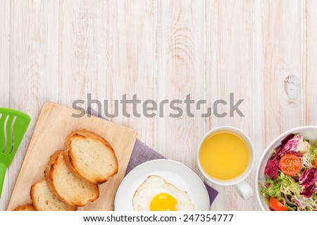 Healthy breakfast with fried egg, toasts and salad on white wooden table with copy space