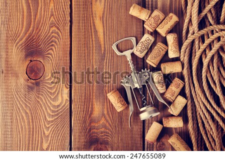 Wine corks and corkscrew over rustic wooden table background with copy space. Retro toned