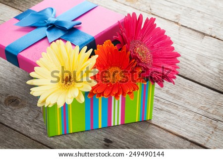 Colorful gerbera flowers in gift box on wooden table with copy space