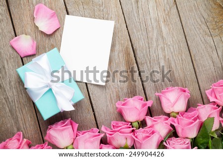 Pink roses and valentines day greeting card or photo frame and gift box over wooden table. Top view with copy space