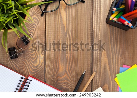 Office table with flower, blank notepad and supplies. View from above with copy space