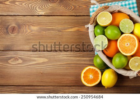 Citrus fruits in basket. Oranges, limes and lemons. Top view over wooden table background with copy space