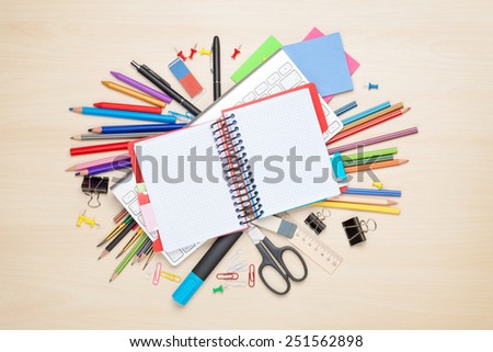 Blank notepad over school and office supplies on office table. Top view with copy space