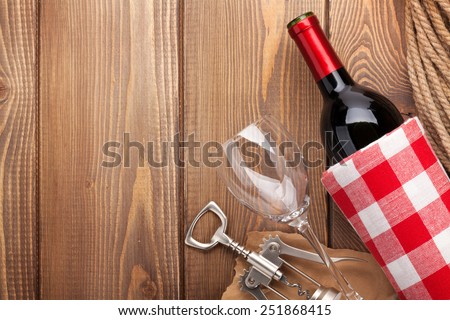 Red wine bottle, wine glass and corkscrew on wooden table background with copy space