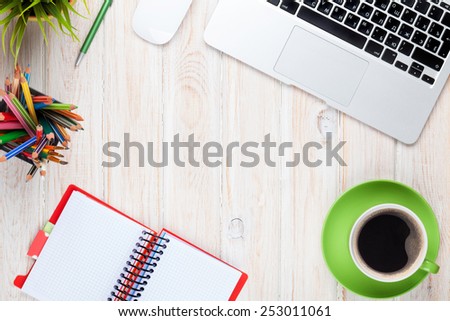 Office desk table with computer, supplies, coffee cup and flower. Top view with copy space
