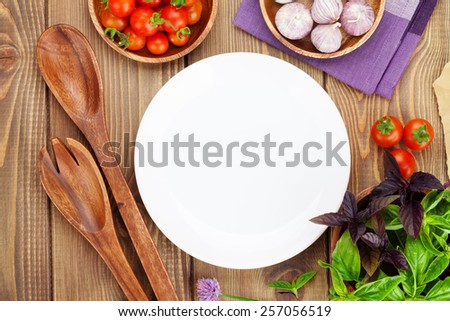 Fresh farmers tomatoes and basil on wood table with empty plate for copy space