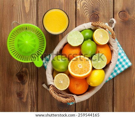 Citrus fruits and glass of juice. Oranges, limes and lemons. Top view over wood table background