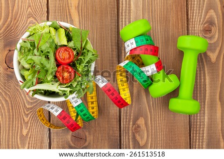 Dumbells, tape measure and healthy food over wooden table. Fitness and health