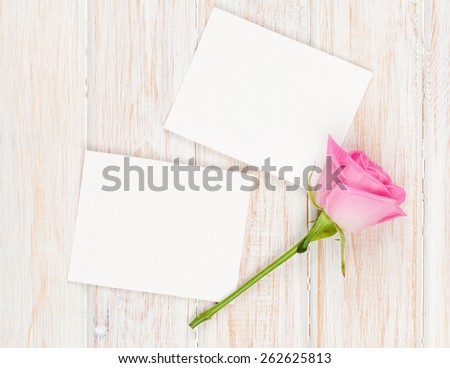 Blank photo frames and pink rose over wooden table. Top view with copy space