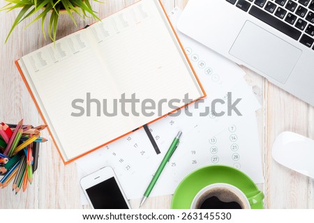 Office desk table with computer, supplies, coffee cup and flower. Top view with copy space