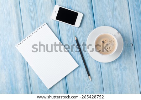 Coffee cup, smartphone and blank photo frame on wooden table background. Top view with copy space