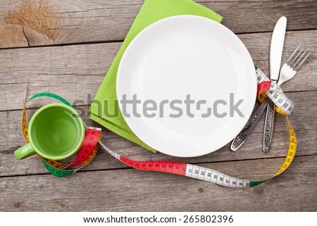 Plate with measure tape, cup, knife and fork. Diet food on wooden table