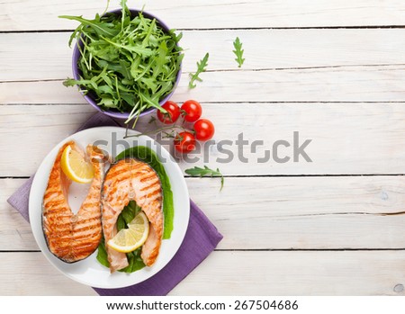 Grilled salmon and salad on wooden table. Top view with copy space