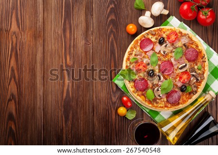Pizza and red wine on wooden table background. Top view with copy space