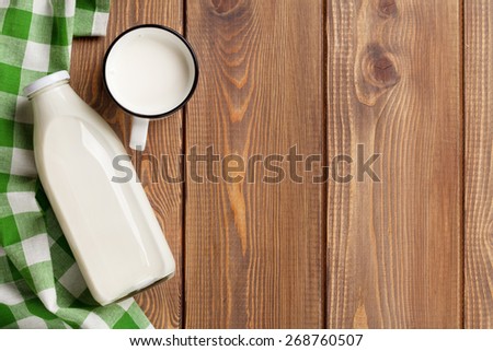 Milk cup and bottle on wooden table. Top view with copy space