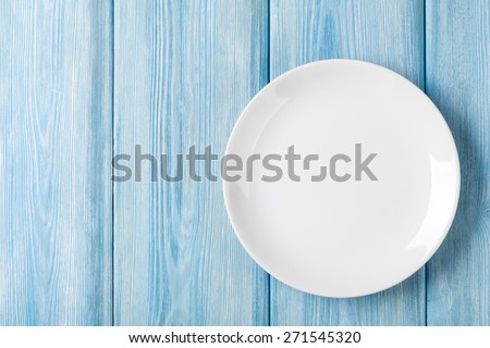 Empty plate on blue wooden background. Top view with copy space