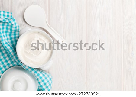 Sour cream in a bowl on wooden table. Top view with copy space