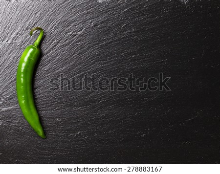 Green chili pepper on black stone table with copy space