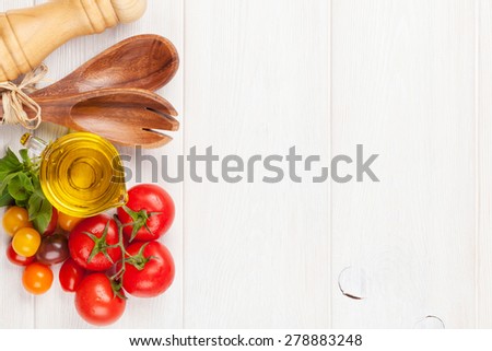 Fresh colorful tomatoes, basil and olive oil on white wooden table. Top view with copy space