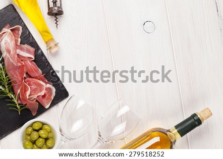 Prosciutto, wine, olives and olive oil on wooden table. Top view with copy space