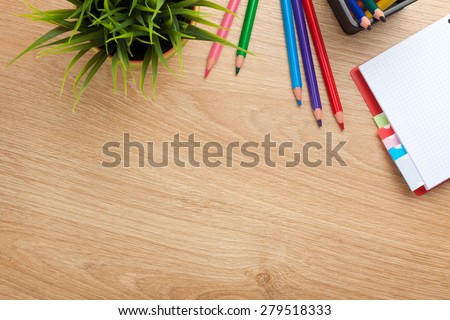 Office table with flower, blank notepad and colorful pencils. View from above with copy space