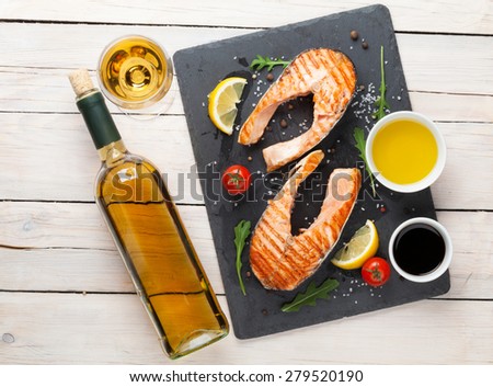 Grilled salmon and white wine on wooden table. Top view