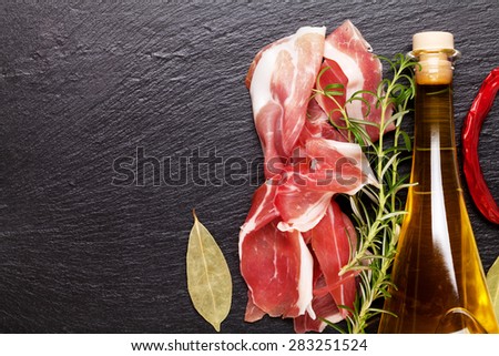 Prosciutto with rosemary and olive oil on stone table. Top view with copy space