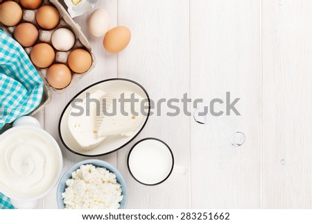Dairy products on wooden table. Sour cream, milk, cheese, eggs, yogurt and butter. Top view with copy space