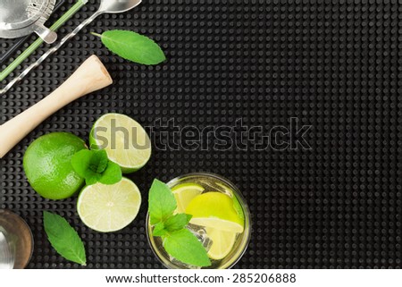 Mojito cocktail and ingredients over black rubber mat. Top view with copy space