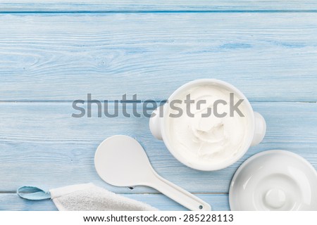 Sour cream in a bowl on wooden table. Top view with copy space