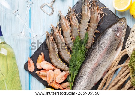 Fresh raw sea food with spices and white wine on wooden table background. Top view