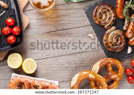 Beer mug, grilled shrimps, sausages and pretzel on wooden table. Top view with copy space