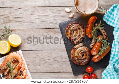 Beer mug, grilled shrimps and sausages on wooden table. Top view with copy space