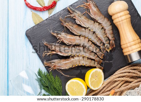 Fresh raw tiger prawns and spices on wooden table