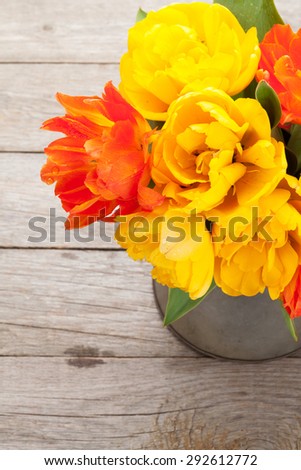 Colorful tulips bouquet in watering can on wooden table
