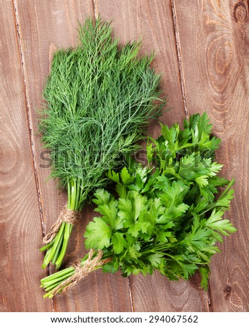 Fresh garden dill and parsley herbs on wooden table. Top view