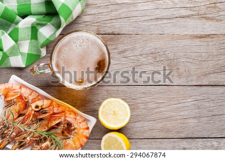 Beer mug and grilled shrimps on wooden table. Top view with copy space