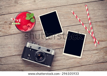 Vintage film camera, two blank photo frames and raspberry smoothie on wooden table. Top view