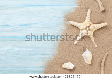 Sea sand with starfish and shells on wooden table. Top view with copy space