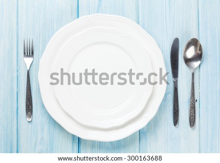 Empty plate and silverware over wooden table background. View from above with copy space