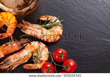 Beer mug and grilled shrimps on stone plate. Top view with copy space
