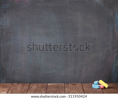 Colorful chalks on classroom table in front of blackboard. View with copy space