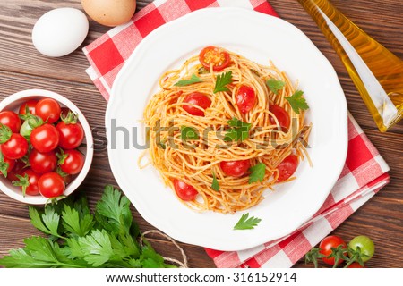 Spaghetti pasta with tomatoes and parsley on wooden table. Top view