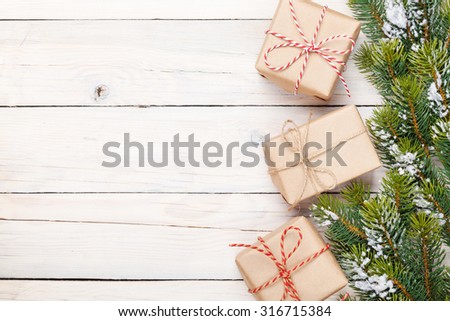 Christmas fir tree with snow and gift boxes on rustic wooden board with copy space