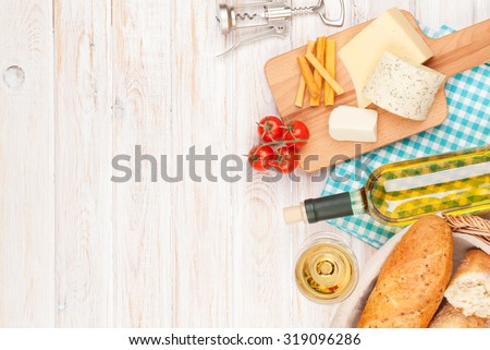 White wine, cheese and bread on white wooden table background. Top view with copy space