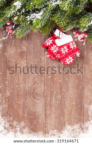 Christmas wooden background with snow fir tree and mittens