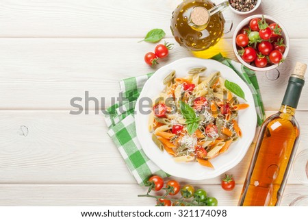 Colorful penne pasta and white wine on wooden table. Top view with copy space