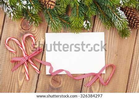 Christmas tree branch with snow and blank greeting card on wooden table. Top view